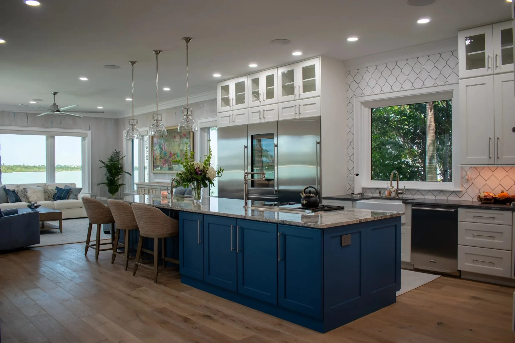 Remodeled waterfront kitchen in Sarasota with a blue island and white cabinetry