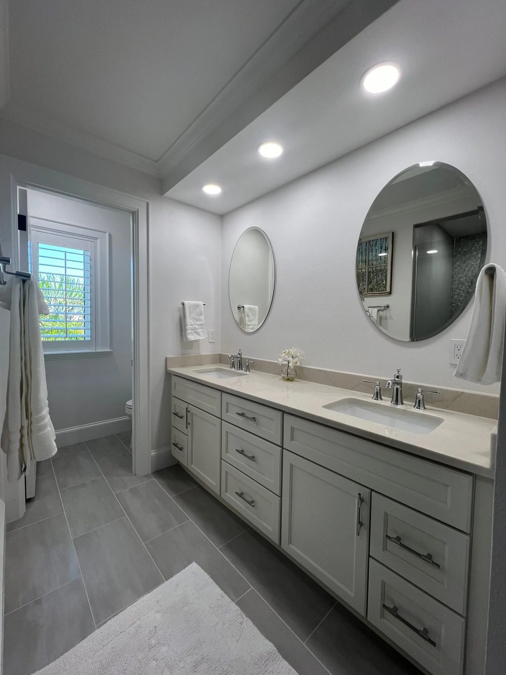 Remodeled bathroom with double vanity and round mirrors