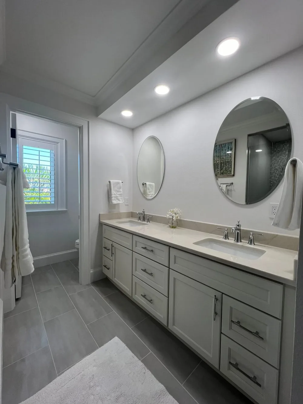 Remodeled bathroom with double vanity and round mirrors
